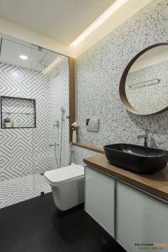 a modern bathroom with black and white tiles on the wall, toilet and sink area