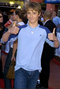 a young man is giving the thumbs up sign at an event with people in the background