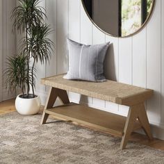 a wooden bench sitting in front of a mirror next to a potted palm tree