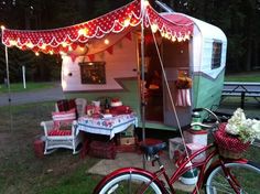 a red bicycle is parked in front of a camper with christmas lights on it