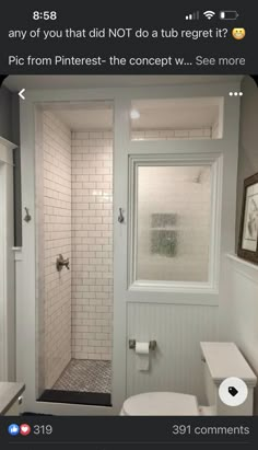 a white toilet sitting next to a shower in a bathroom under a window with a rug on the floor