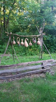 a wooden structure with birds hanging from it's sides in the grass next to trees