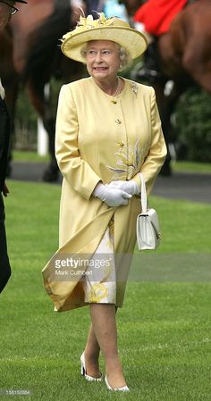 an older woman wearing a yellow dress and hat walking in the grass with other people