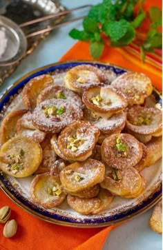 a plate full of powdered sugar and pistachio cookies on an orange napkin