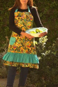 a woman in an apron holding a plate of fruit