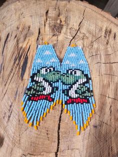 two beaded birds sitting on top of a piece of wood