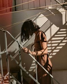 a woman is walking up some stairs with her hand on the railing and looking down