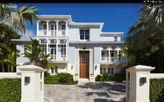 a large white house with lots of windows and palm trees in front of the entrance