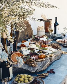 the table is set with many different foods and wine bottles on it, along with plates of food