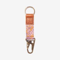 an orange and pink keychain with a metal hook on the end, in front of a white background