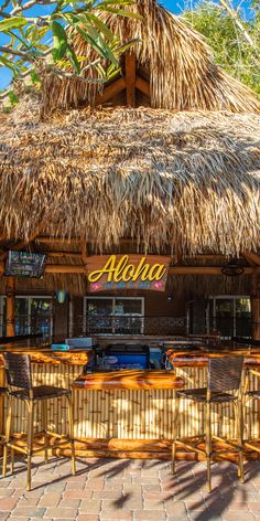 a tiki bar with thatched roof and wicker chairs