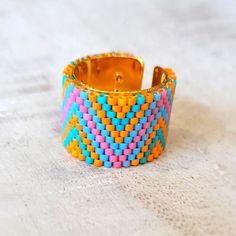 a close up of a colorful bracelet on a white surface with an object in the background