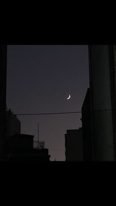 the moon is seen in the sky over some buildings at night, with no clouds