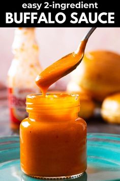 an orange sauce being drizzled into a jar with the words easy 2 ingredient buffalo sauce