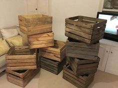 a pile of wooden crates sitting on top of a floor next to a white couch