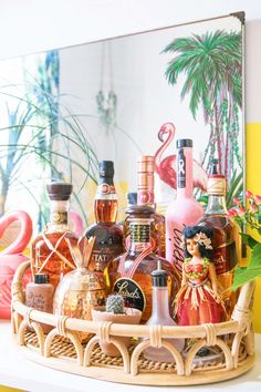 various bottles of alcohol are sitting on a wicker basket with flamingos in the background