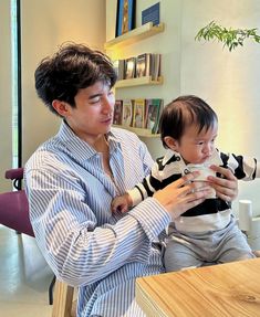 a man holding a baby while sitting at a table