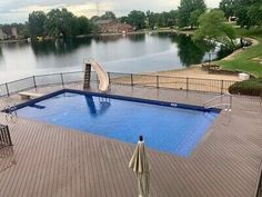 an above ground swimming pool surrounded by wooden decking and fenced in area with water slide