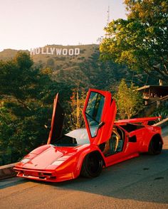 a red sports car parked in front of hollywood sign