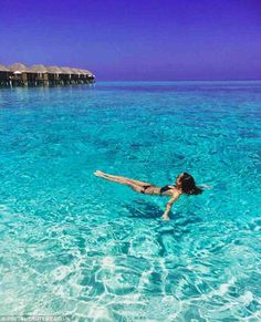 a woman floating in the ocean on top of a body of water