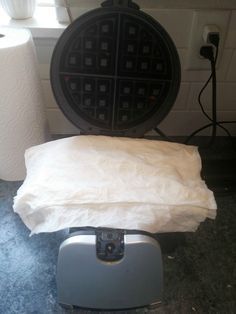 a waffle iron sitting on top of a counter next to a roll of toilet paper