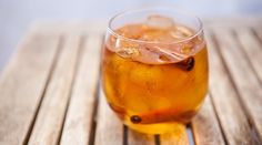 a glass filled with liquid sitting on top of a wooden table