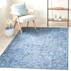 a blue rug in a room with a white chair and book shelf on the wall