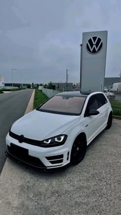 a white volkswagen car parked in front of a sign