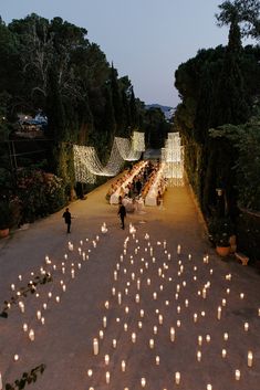 many lit candles are arranged in the shape of a heart on a path surrounded by trees