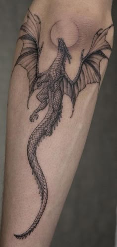 a dragon tattoo on the leg of a person's leg, with an arrow in the middle