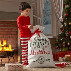 a young boy standing next to a christmas bag