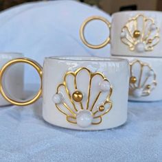 three white cups with gold rings on them