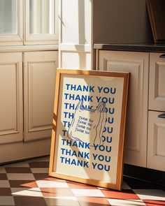 a framed thank you sign sitting on top of a checkered floor next to cabinets