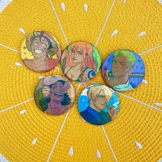 four anime buttons sitting on top of a yellow mat