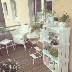 a balcony with chairs, tables and potted plants on the outside deck area that is decorated in pastel colors