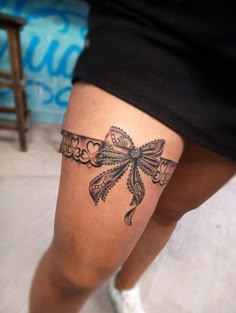 a woman's leg with a bow tattoo on the side of her thigh,