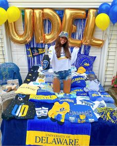 a woman standing in front of a bed with blue and yellow decorations