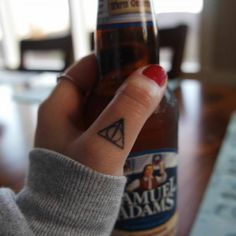 a person with a tattoo on their finger holding a beer