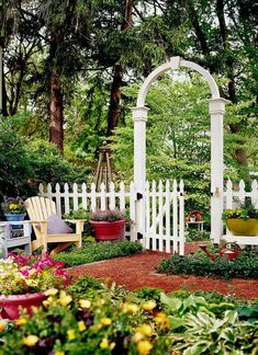 the garden is full of colorful flowers and greenery, including white arbors in the background