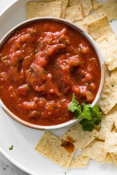 a bowl of salsa with tortilla chips and cilantro on the side