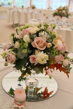 a vase filled with lots of flowers on top of a white table cloth covered table