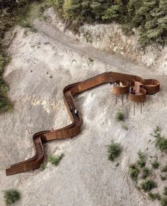 an aerial view of people sitting on wooden benches in the middle of a rocky area