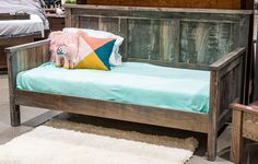 a wooden bed with blue sheets and pillows on it in a room filled with furniture