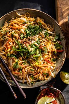 a bowl filled with noodles and vegetables next to some chopsticks on the side