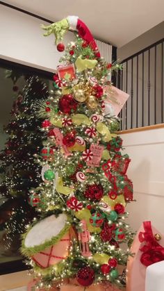 a decorated christmas tree with candy canes and ornaments on it's top, in front of a staircase