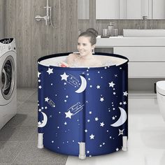 a woman sitting in a bathtub with stars and moon designs on the floor next to a washing machine