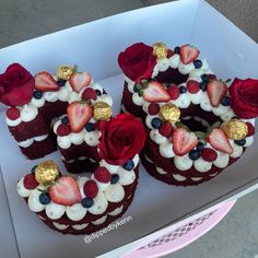 four cakes with strawberries, raspberries and blueberries on top in a box