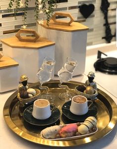 two cups of coffee sit on a tray with seashells and sea urns in the background