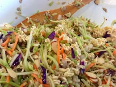 a salad with noodles, carrots and nuts on a wooden spoon