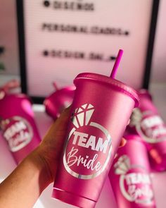 a hand holding a pink cup with team bride on it and other cups in the background